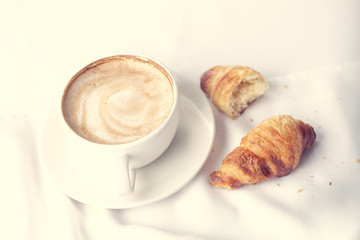 Coffee and croissant for breakfast with shallow depth of field.