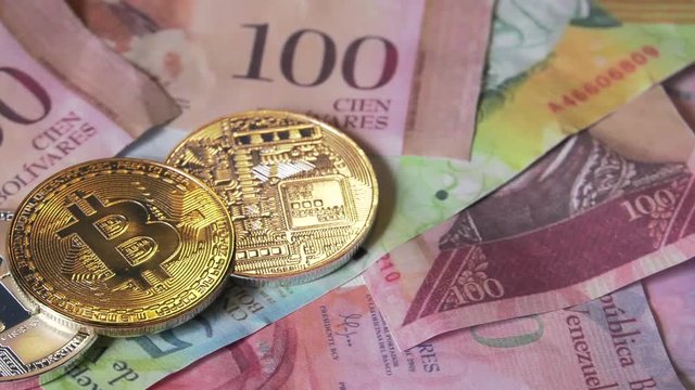 Physical metal Bitcoin currency over bolivar bills. Virtual internet money with Venezuelan banknotes. Digital coin cyberspace, cryptocurrency. BTC golden coin as symbol of electronic virtual money. 4K