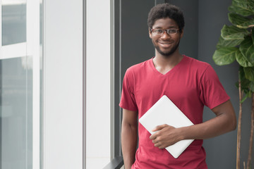 happy college student gets back to school; portrait of happy smiling nerd man, African college student with laptop computer in university campus, back to school concept; African young adult man model