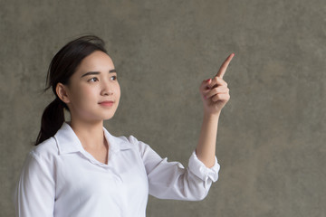 happy girl pointing up; portrait of cheerful smiling woman points hand and finger up to something; positive relaxed happy asian woman smiles in isolated loft background; asian young adult woman model