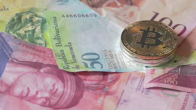 Physical metal Bitcoin currency over bolivar bills. Virtual internet money with Venezuelan banknotes. Digital coin cyberspace, cryptocurrency. BTC golden coin as symbol of electronic virtual money. 4K