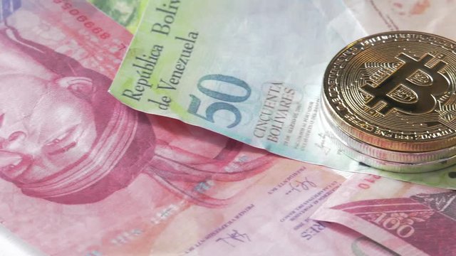 Physical metal Bitcoin currency over bolivar bills. Virtual internet money with Venezuelan banknotes. Digital coin cyberspace, cryptocurrency. BTC golden coin as symbol of electronic virtual money. 4K