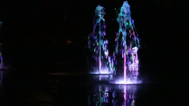 Colored water night fountain dancing with lights multicolored blur footage background, close up, shallow depth of the field, 59,94 fps