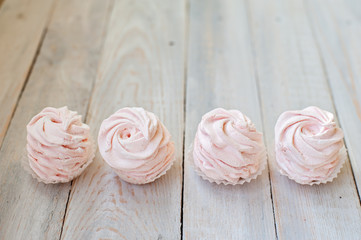 Tasty pink zephyr on a wooden table. It can be used as a background