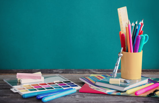 school supplies on wooden table on green background