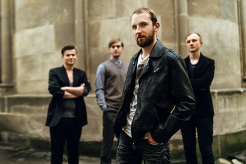 stylish handsome group of men standing and posing on the background of city street