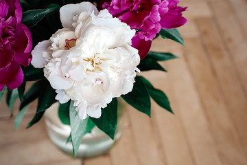 beautiful bunch of peonies in vase on wooden background, rustic wallpaper concept, space for text