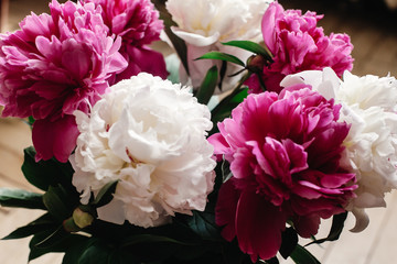 beautiful bunch of peonies in vase on wooden background, rustic wallpaper concept, space for text