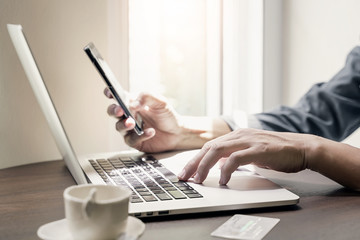 man using laptop and smartphone to buying online at home