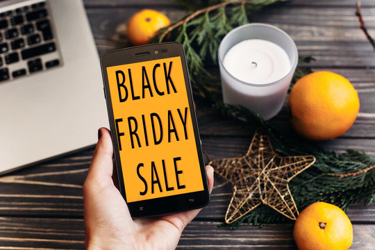 black friday sale. special offer discount text on mobile phone screen in hand message on seasonal rustic background