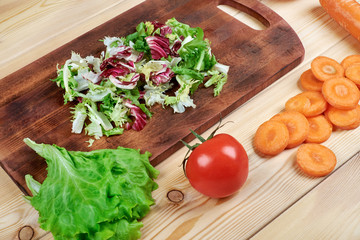 Cooking, Vegetarian Concept. Ready to make salad.A cutting board, a knife, vegetables and spices on a kitchen table, top view.