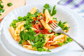 Italian food - pasta with peppers and tomatoes and parsley in a plate on a light background, penne