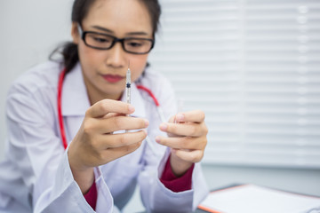 Young doctor woman holding a syringe in the workplace.