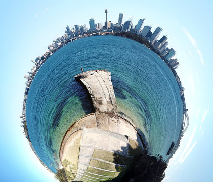 A planetoid of Sydney skyline and harbour with a blue sky. Aerial view of Sydney Harbour, Harbour Bridge with financial district skyscrapers.