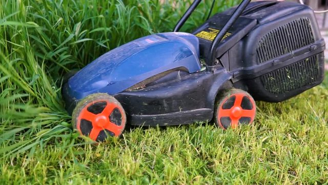 Worker mowing a grass with lawn mower