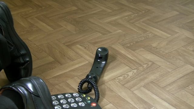 Legs Of Man In Suit Walking In The Office And Falling Over Hanging Telephone Cable. Health And Safety At Work Or Home Concept