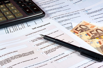 pen, money, calculator and self employment tax form