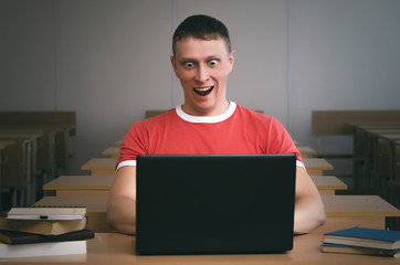 Amazed student boy sitting by the school desk.