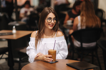 Stylish happy young woman wearing white shirt .She holds coffee. portrait of smiling girl in sunglasses