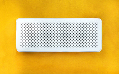Wireless speaker on yellow background close up view.