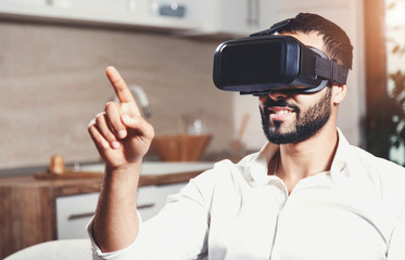 Handsome bearded man using virtual reality goggles in the modern flat
