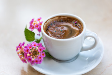 Obraz na płótnie Canvas Traditional invigorating Turkish coffee. A white cup of coffee is decorated with flowers. Beautiful feed