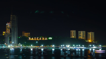 Fototapeta na wymiar Pattaya sign at Pattaya beach bay with many boats floating in the sea night shot