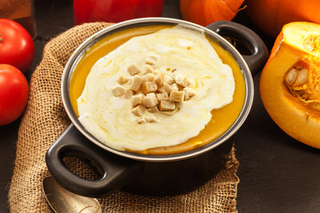 Pumpkin soup with cream and croutons in a pot