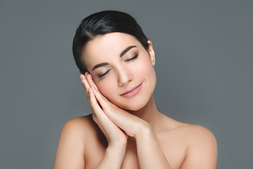 portrait of young attractive woman with eyes closed isolated on grey