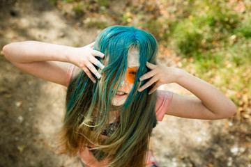 bright blonde girl whose hair, face and hands in paint Holi 