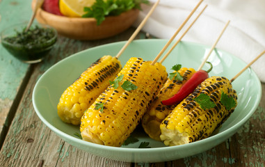 Sweet baked corn in a deep plate, served with chamichurri sauce and lemon. Rustic style.