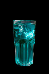 A single-colored transparent cocktail, refreshing shining in a tall blue glass with large square ice cubes. Side view Isolated black background. Drink for the menu restaurant, bar, cafe
