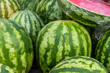Close up of a pile of beautiful delicious green watermelons on the market bench or counter. Agricultural background concept