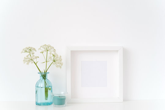 Summer white square in transparent blue vase and blue candle on white background . Mockup for quote, promotion, headline, design. Template for lifestyle bloggers, social media