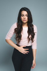 Obraz premium young woman suffering from abdominal pain, isolated on grey