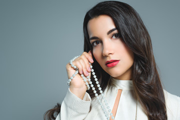 Obraz premium beautiful brunette woman holding necklace, isolated on grey