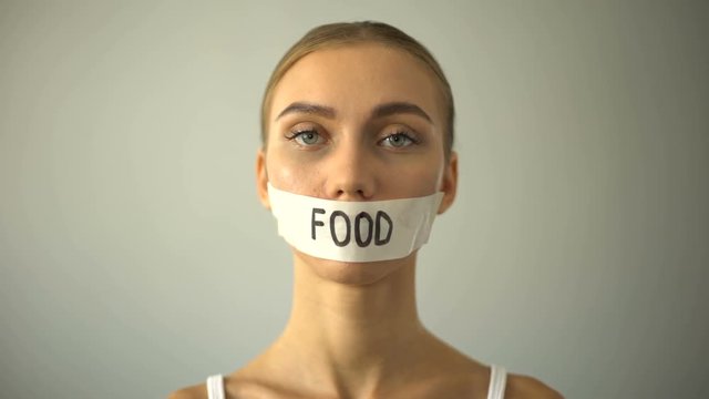 Thin model with taped mouth, concept of food restriction and anorexia, diet