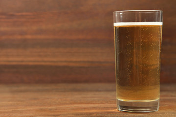 Apple cider in a glass on a brown wooden background.