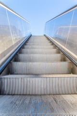 Metallic escalator outside with blue sky