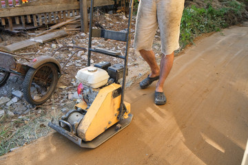 Builder ramming sand around the house at the construction site