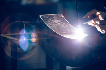 Welder working on bronze component