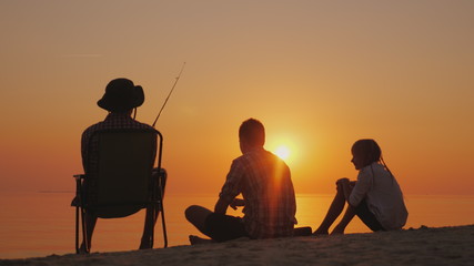 Fototapeta na wymiar Three teenagers are fishing on the shore of the lake at sunset. Happy childhood concept