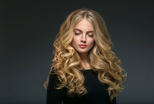 Blonde hairstyle woman beauty with long curly blonde hair over dark background
