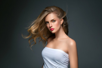 Fototapeta premium Blonde hairstyle woman beauty with long curly blonde hair over dark background