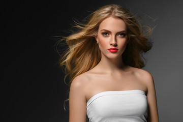 Blonde hairstyle woman beauty with long curly blonde hair over dark background