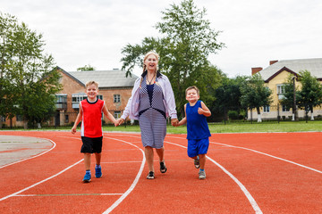 Obraz premium young grandmother runs a sports stadium with the grandkids