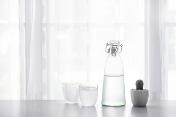 Glass of water with a bottle on table