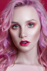 Fototapeta premium Portrait of a woman with bright colored flying hair, all shades of pink purple. Hair coloring, beautiful lips and makeup. Hair fluttering in the wind. Sexy girl with long hair