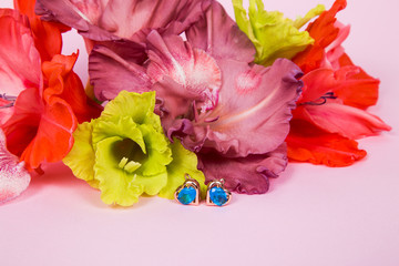 flower arrangement of gladiolus flowers of red, chocolate and light green color with earrings in the form of a heart