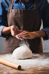 Obraz premium cropped shot of woman in apron kneading dough for pizza